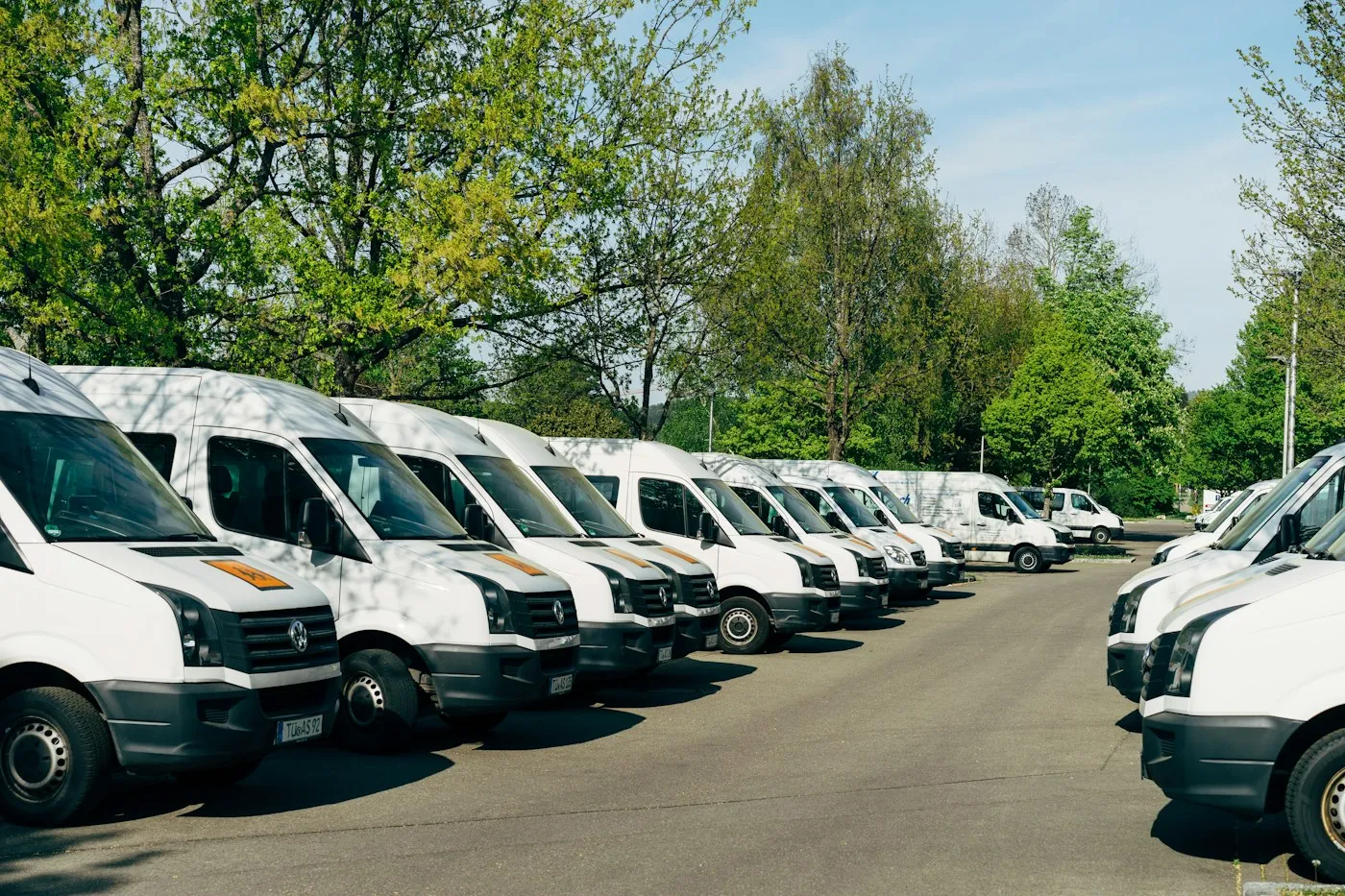 A long row of white delivery vans parked in a lot