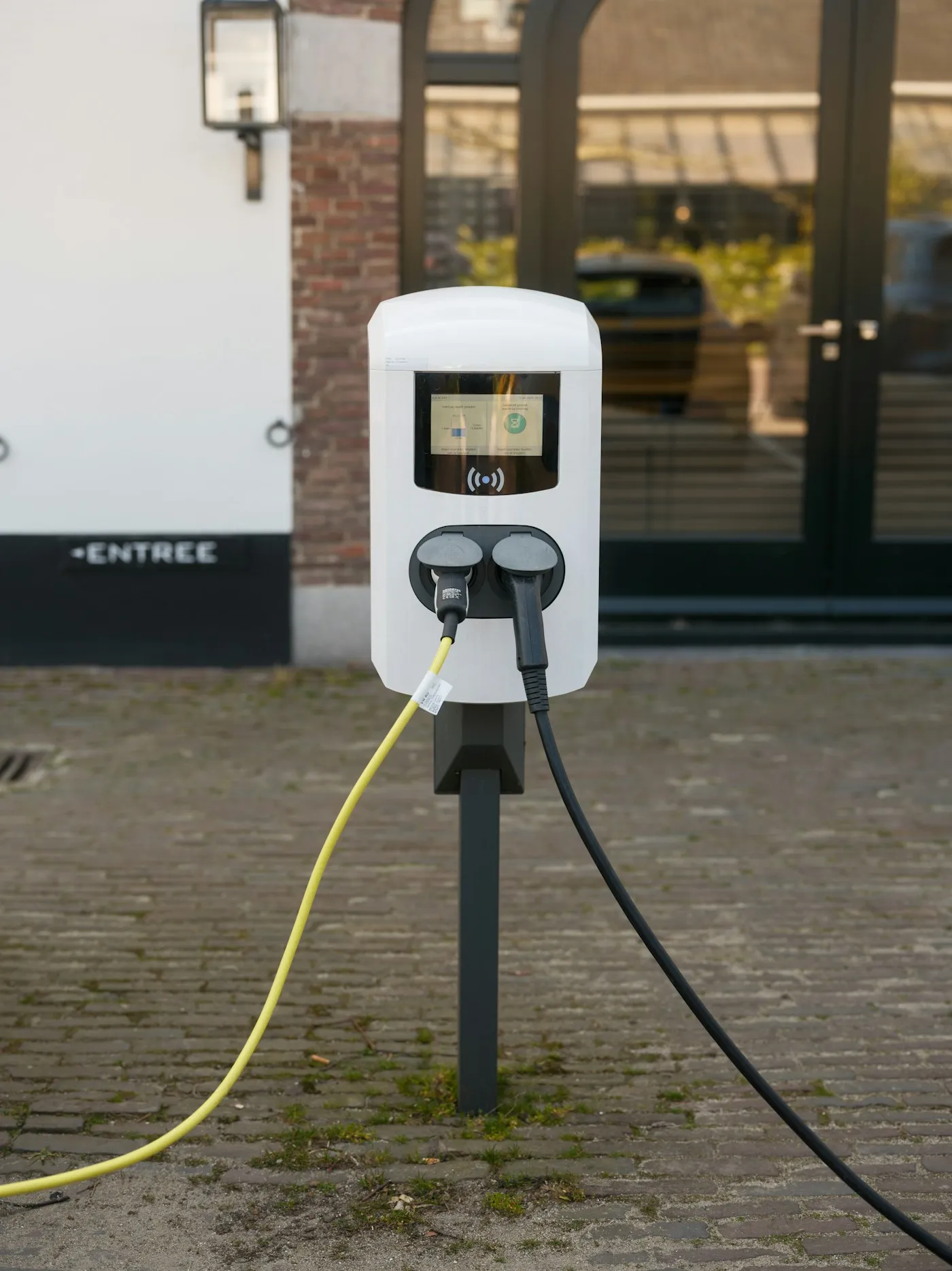 A public EV charger with two cables outside a building